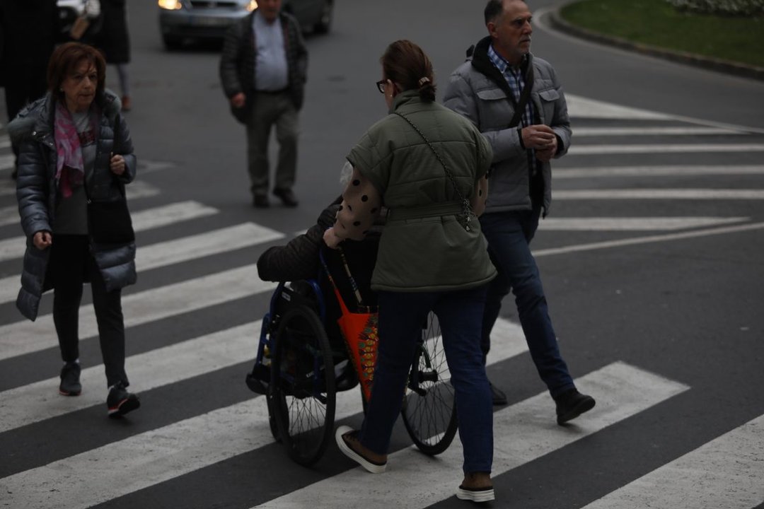 Una mujer lleva a una persona mayor en silla de ruedas. JOSÉ PAZ