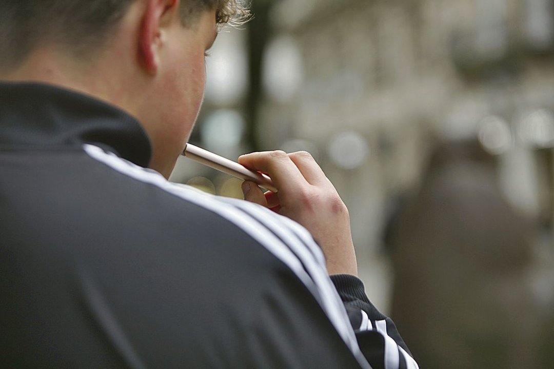 Joven haciendo uso de un cigarrillo electrónico en una calle del centro de la ciudad.