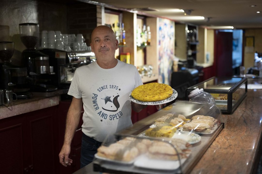 Manuel Herrero, de la cafetería Borea, ante un mostrador con pinchos y su mítica tortilla en la mano.