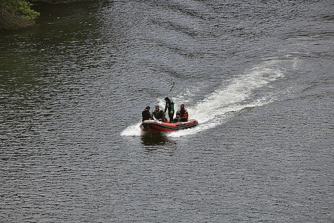 Un equipo de buzos de la Guardia Civil atravesando el río Avia. MIGUEL ÁNGEL
