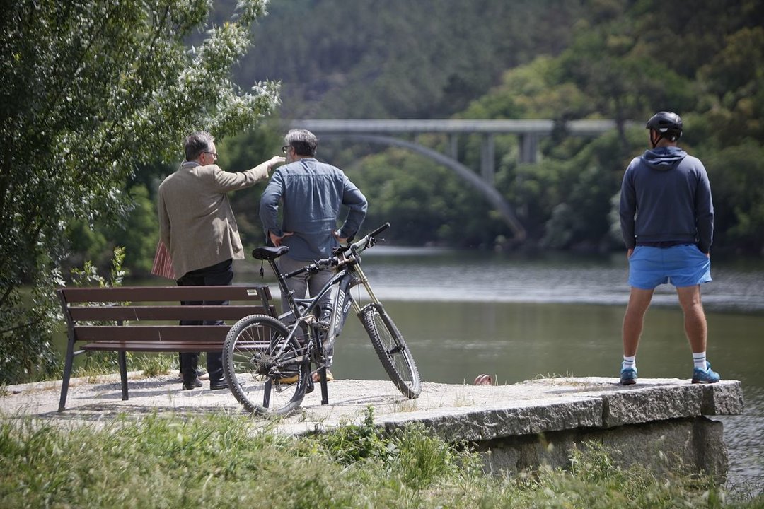 El alcalde junto a dos deportistas, observando el río en el que desapareció Mitogo.