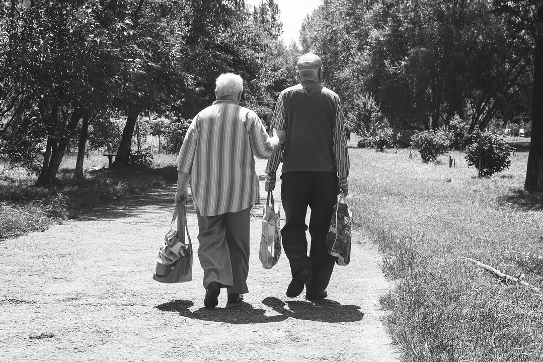 Una pareja de ancianos camina por un camino rural.