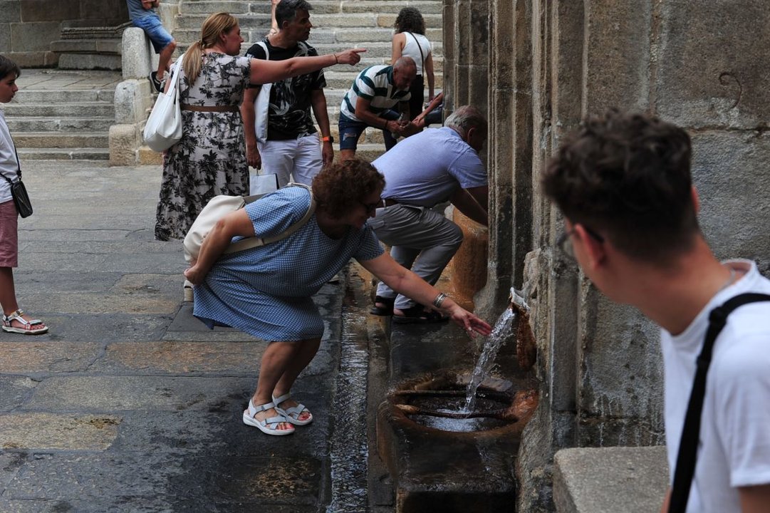 Una turista toca el agua de la fuente de As Burgas.