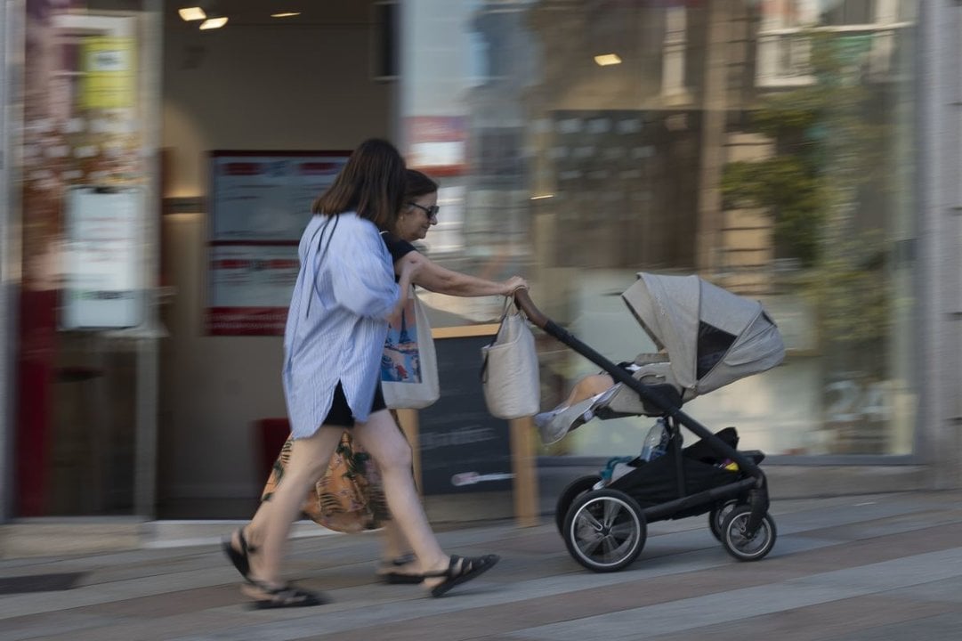 Dos mujeres pasean un bebé en el centro de la ciudad.