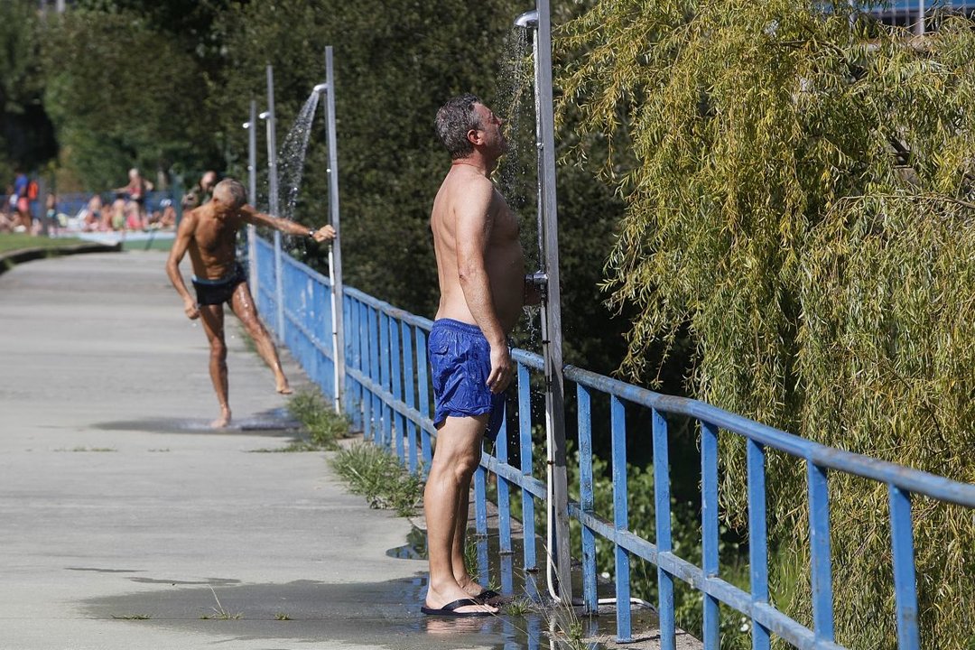 Dos hombres se refrescan en las duchas del recinto deportivo de Oira, en la jornada de ayer.