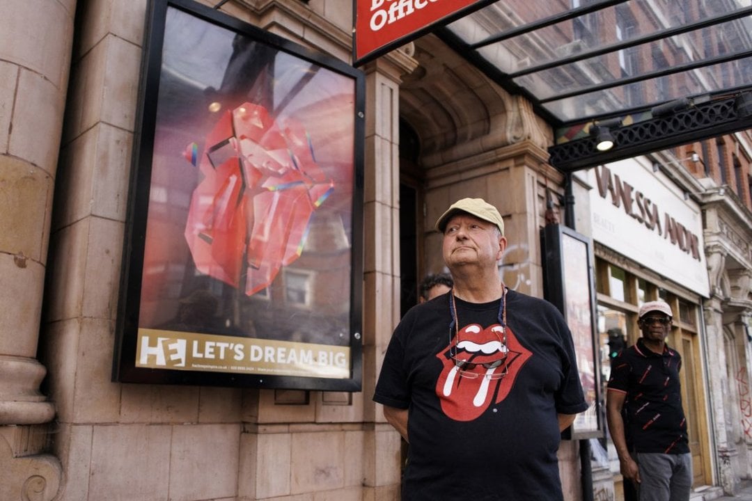 Un fan con la icónica lengua de los Stones, ante el cartel con la nueva imagen.