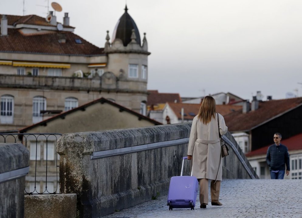 Una mujer con una maleta, cruzando el Puente Romano la semana pasada.