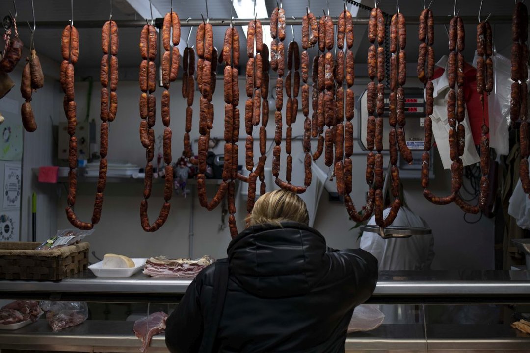 Una mujer observa el género en una carnicería de la Praza de Abastos número 1.
Foto: Xesús Fariñas