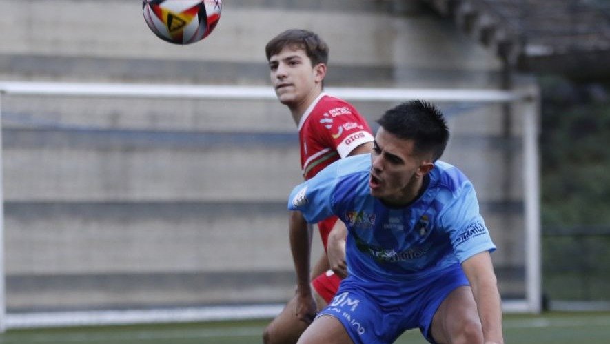 El azulón Osián Vázquez intenta proteger la pelota ante un rival en el campo de Os Carrís.