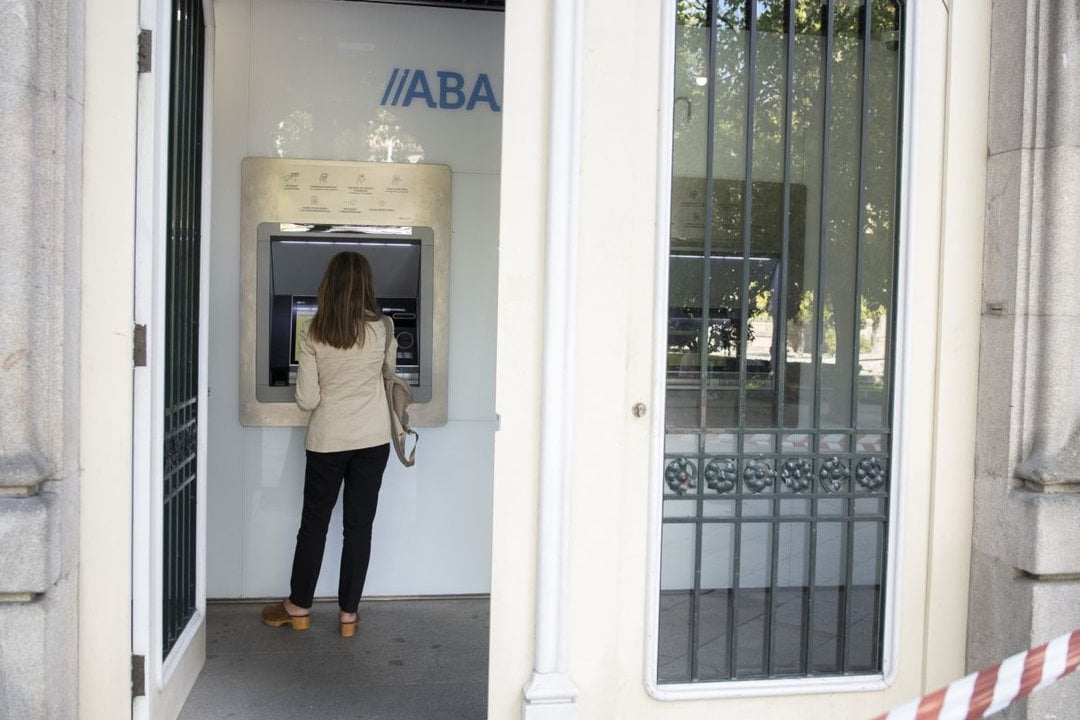 Una mujer saca dinero de un cajero en una sucursal bancaria de la ciudad