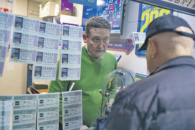 El lotero José Ignacio Mugüerza, ayer vendiendo un décimo a un cliente (Xesús Fariñas).