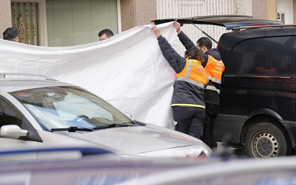 Dos agentes de Protección Civil tapan con una lona la zona donde se han encontrado los cuerpos, a 1 de diciembre de 2023, en Sigüeiro, Oroso, A Coruña (EP)
