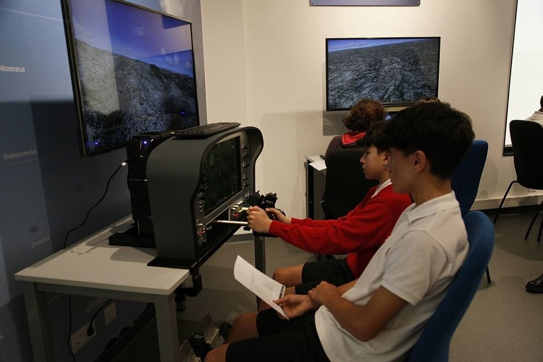 Dos jóvenes manejan los mandos del simulador de vuelo.