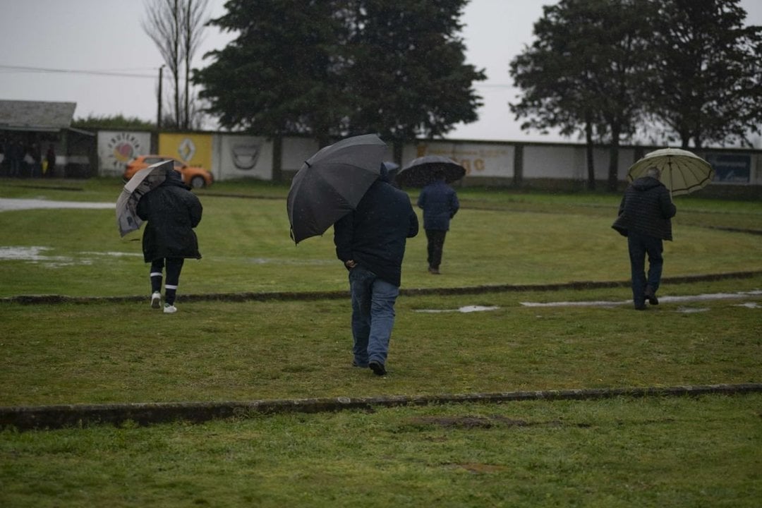 Los paraguas no faltaron ayer en el fútbol provincial. En la imagen, cuatro hombres en el campo del Antela, en Xinzo.
