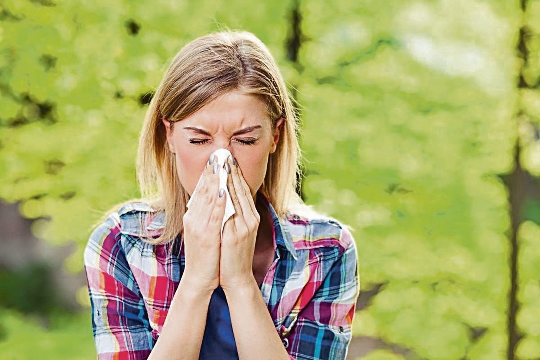 Una mujer estornuda por la alergia que tiene al polen.