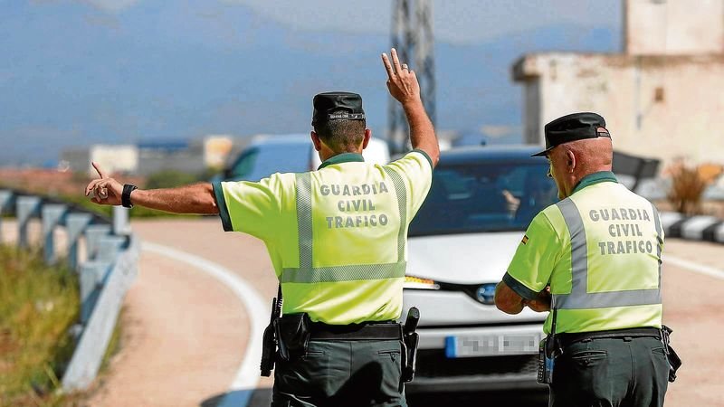 Dos agentes de la Guardia Civil detienen a un vehículo durante un control de carretera.