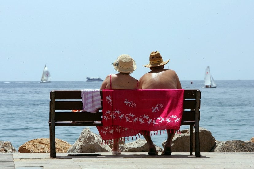 Una pareja de jubilados contempla el mar desde el banco de un espigón.