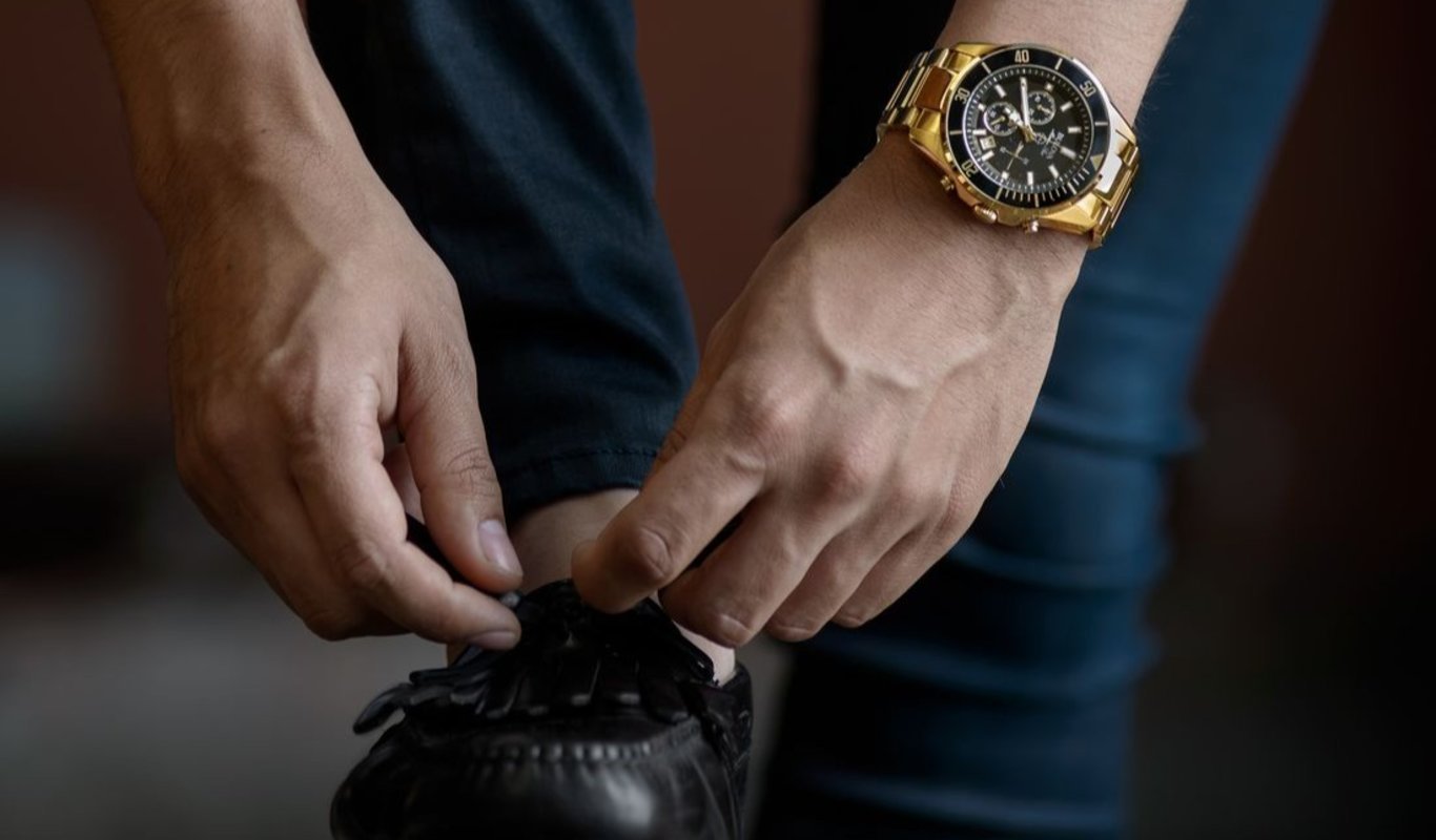 Un hombre se ata los zapatos con un reloj de lujo. (Foto: Unsplash)